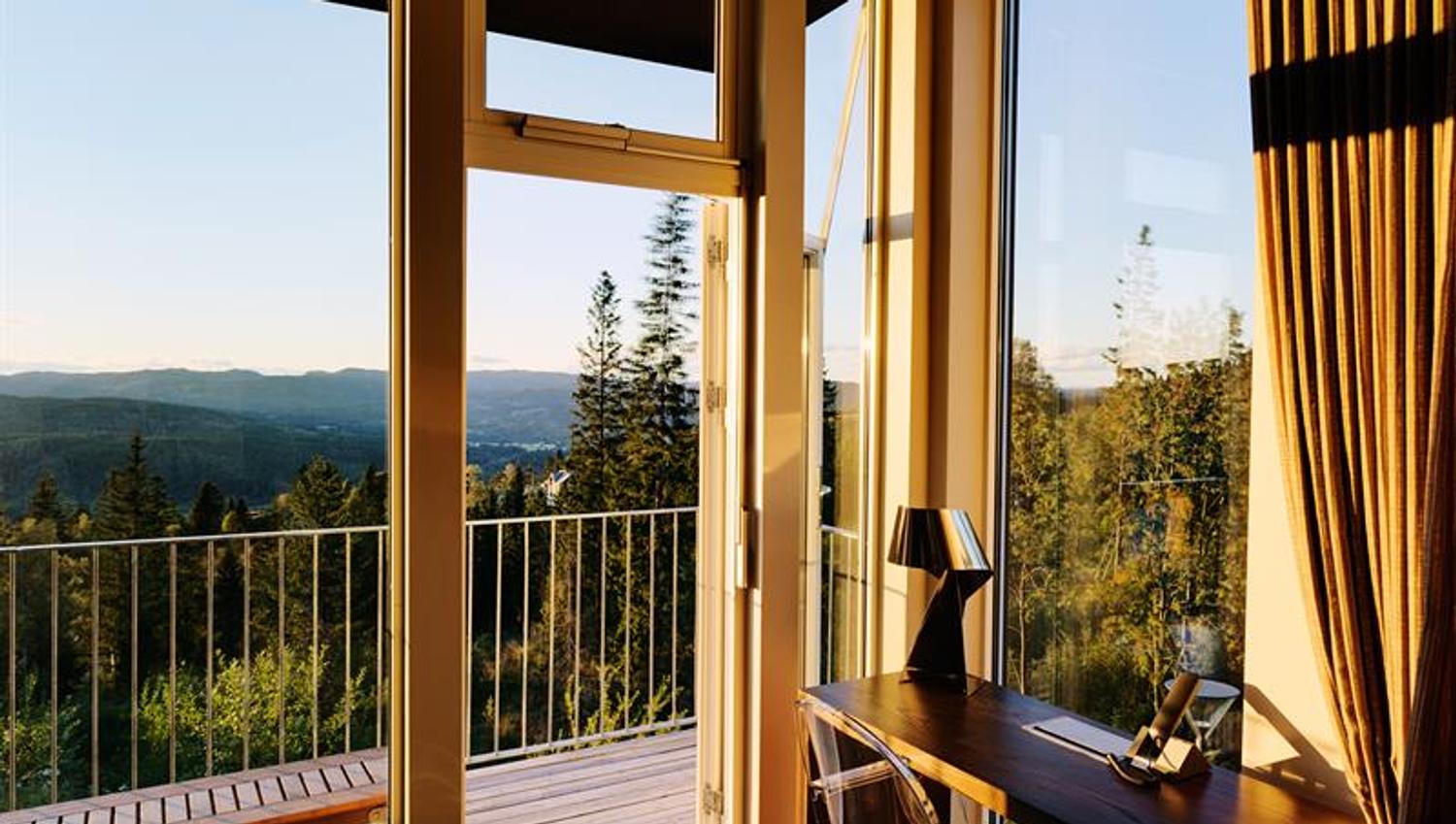Forest view from a room with a desk and a balcony. Photo