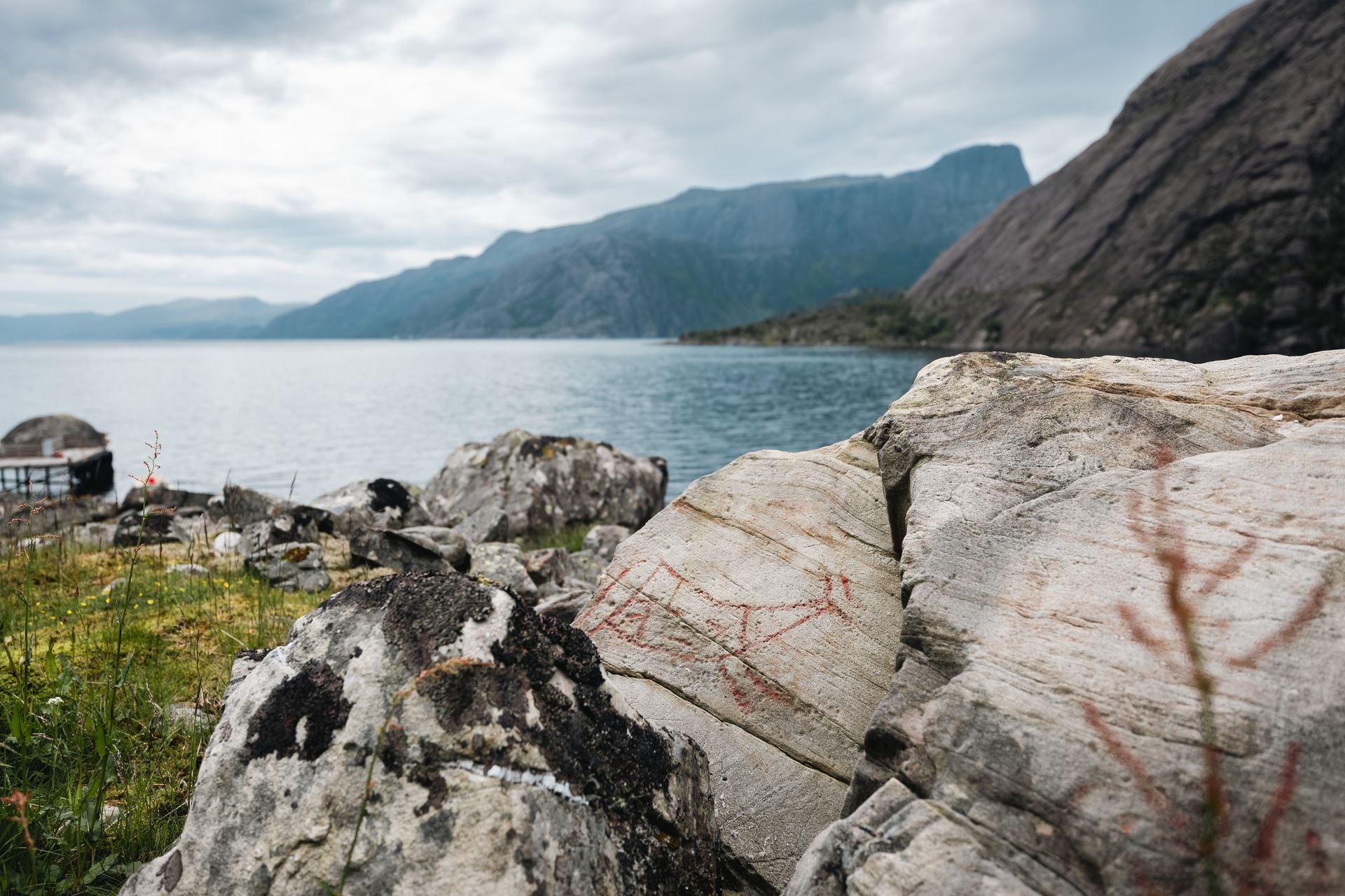 Ancient rock carvings in the Vingen rock art landscape, with the fjord and mountains in the background.