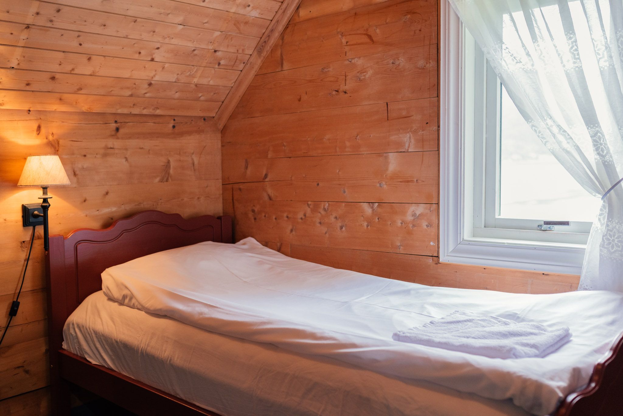 Cozy wooden bedroom with fjord view at Stana Farm – traditional charm meets modern comfort.