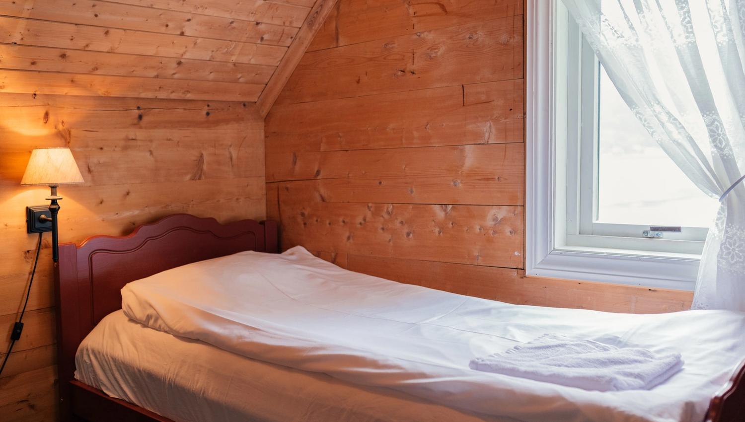 Cozy wooden bedroom with fjord view at Stana Farm – traditional charm meets modern comfort.