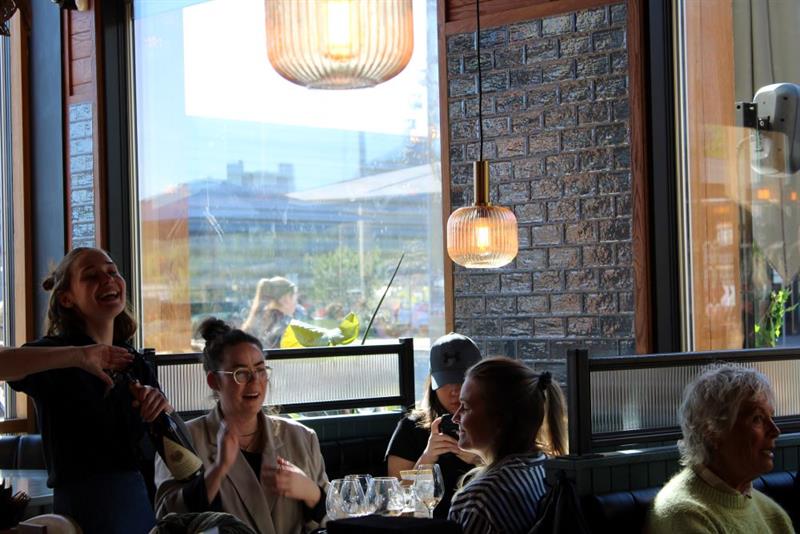 Servitør som åpner en flaske champagne for sittende gjester