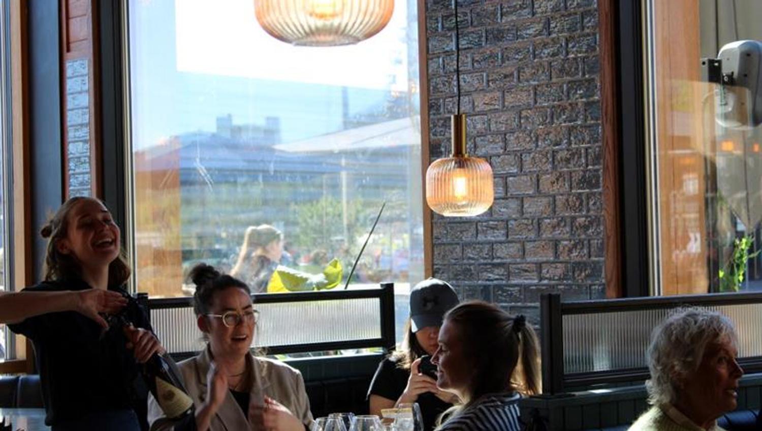 Servitør som åpner en flaske champagne for sittende gjester