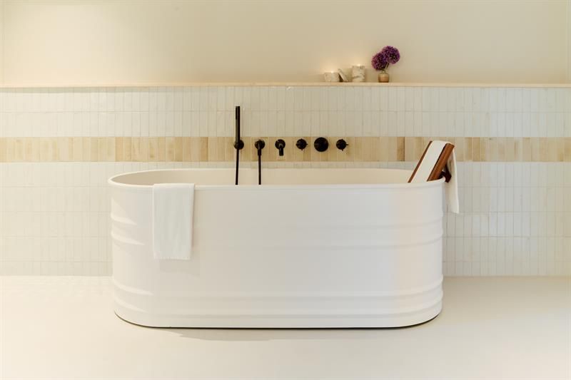 The bathroom features a freestanding bathtub, wall-mounted fixtures and tiled surfaces. Designed for practical and comfortable use.