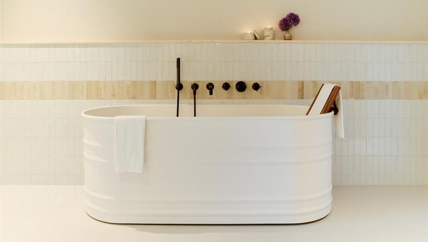 The bathroom features a freestanding bathtub, wall-mounted fixtures and tiled surfaces. Designed for practical and comfortable use.