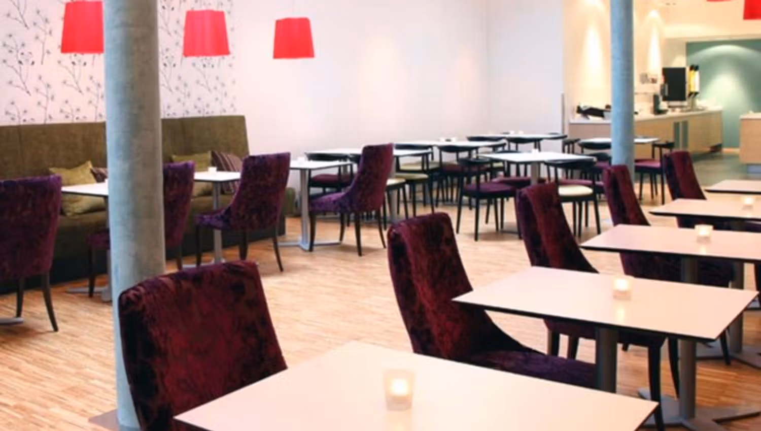 Bright and modern dining area with purple chairs, white tables, and red lamps.