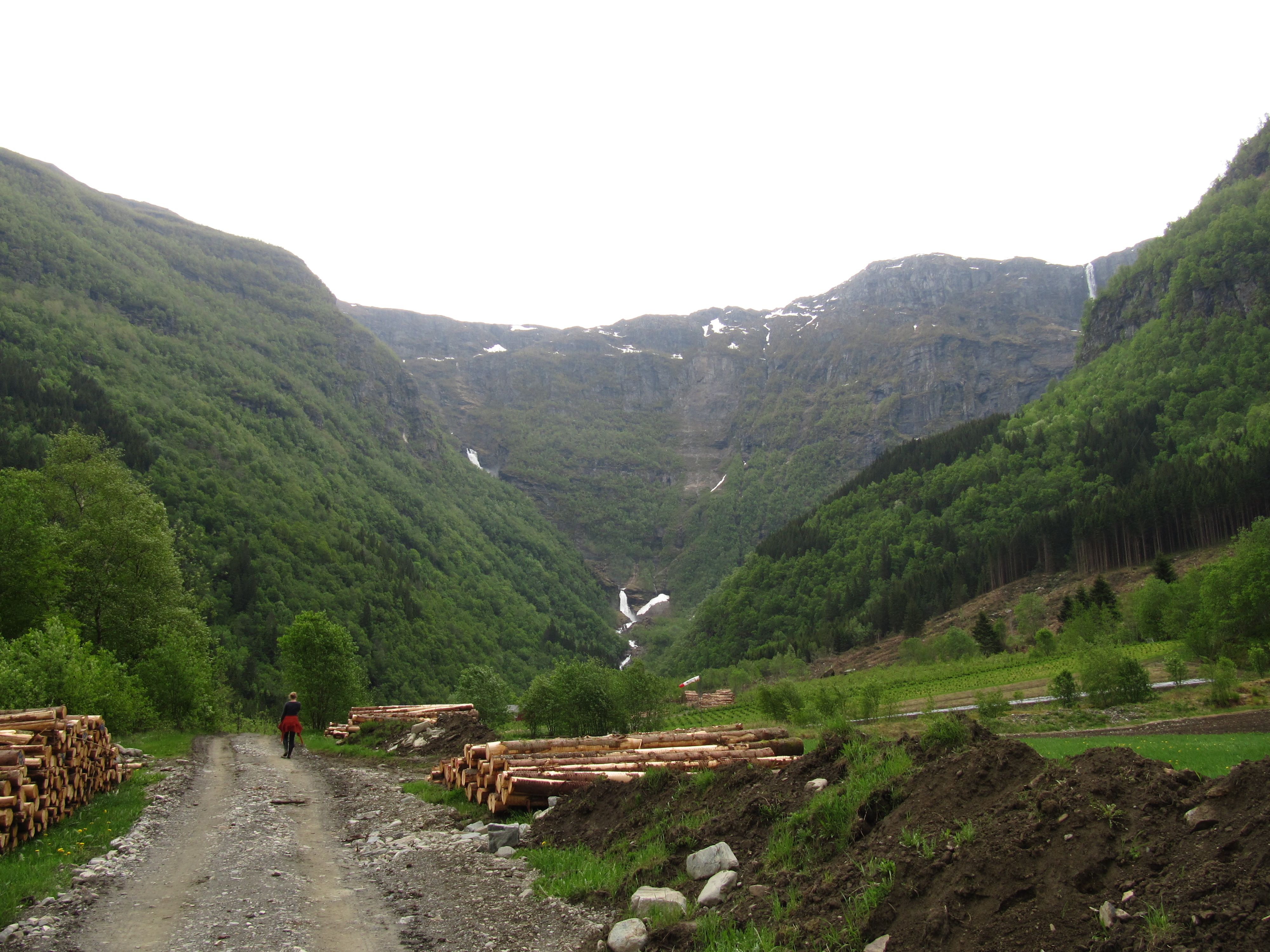 Hiking along a gravel road through a green valley with a distant waterfall in Elvedalen, Lofthus.