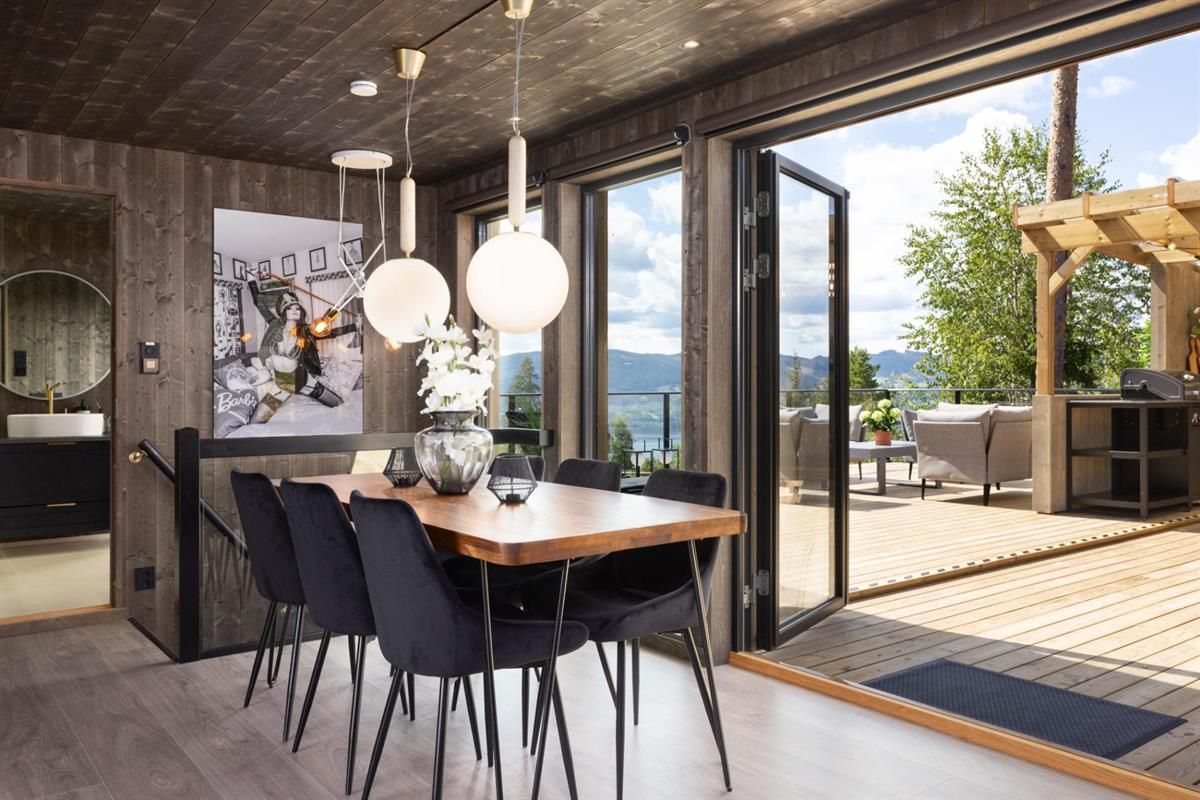 A dining room with large sliding doors open to a terrace and a scenic view.