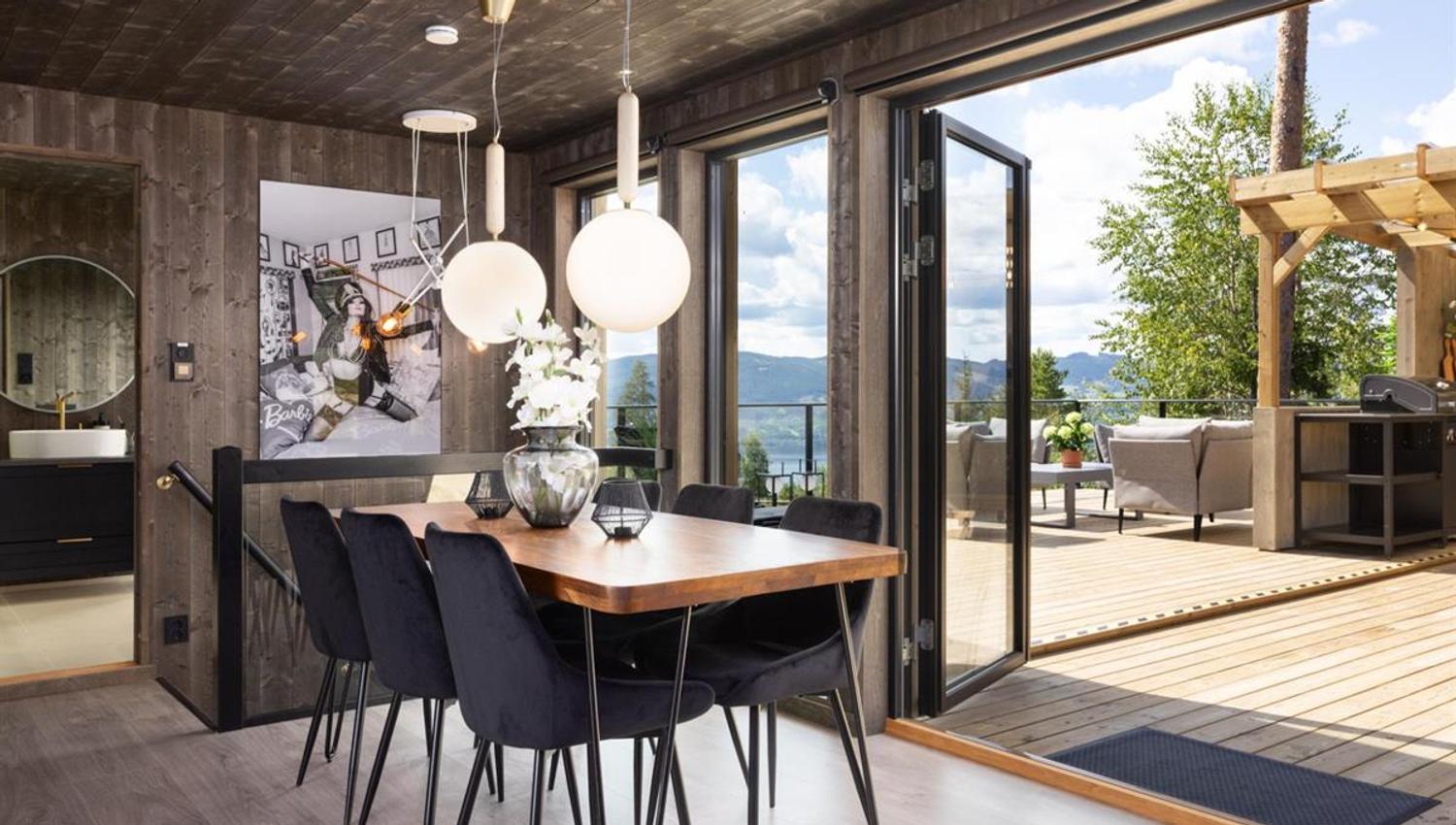 A dining room with large sliding doors open to a terrace and a scenic view.