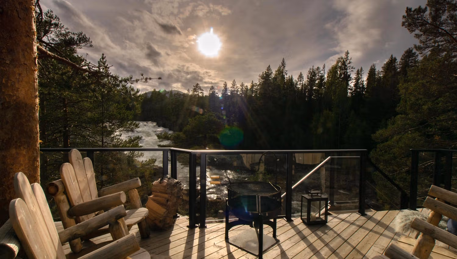 Wooden deck with solid wooden chairs with view to a waterfall against the sun