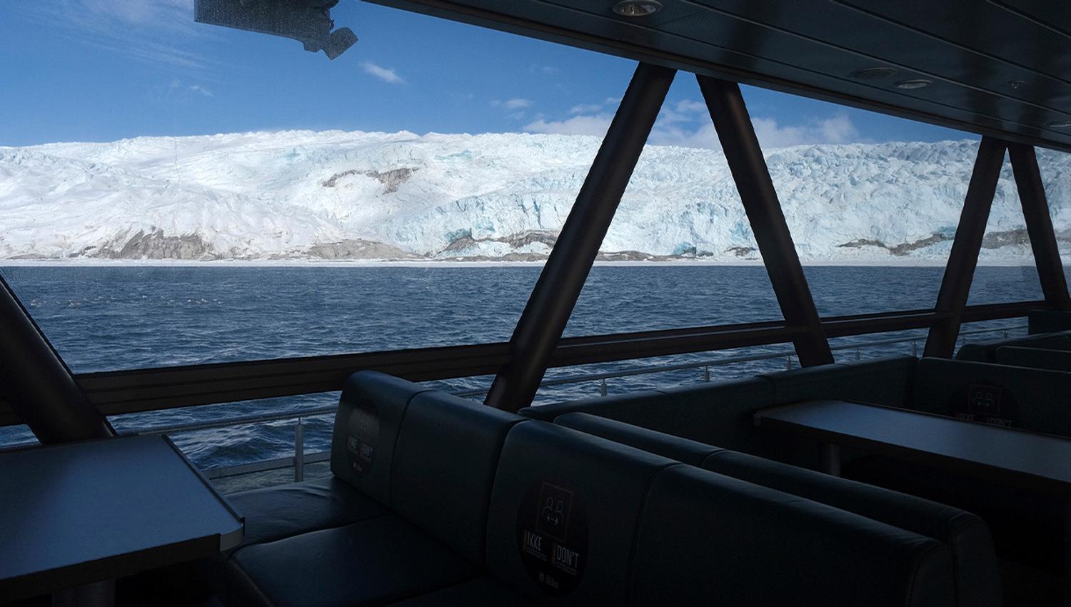 View towards a glacier and a fjord through the boat MS Bard's panoramic windows