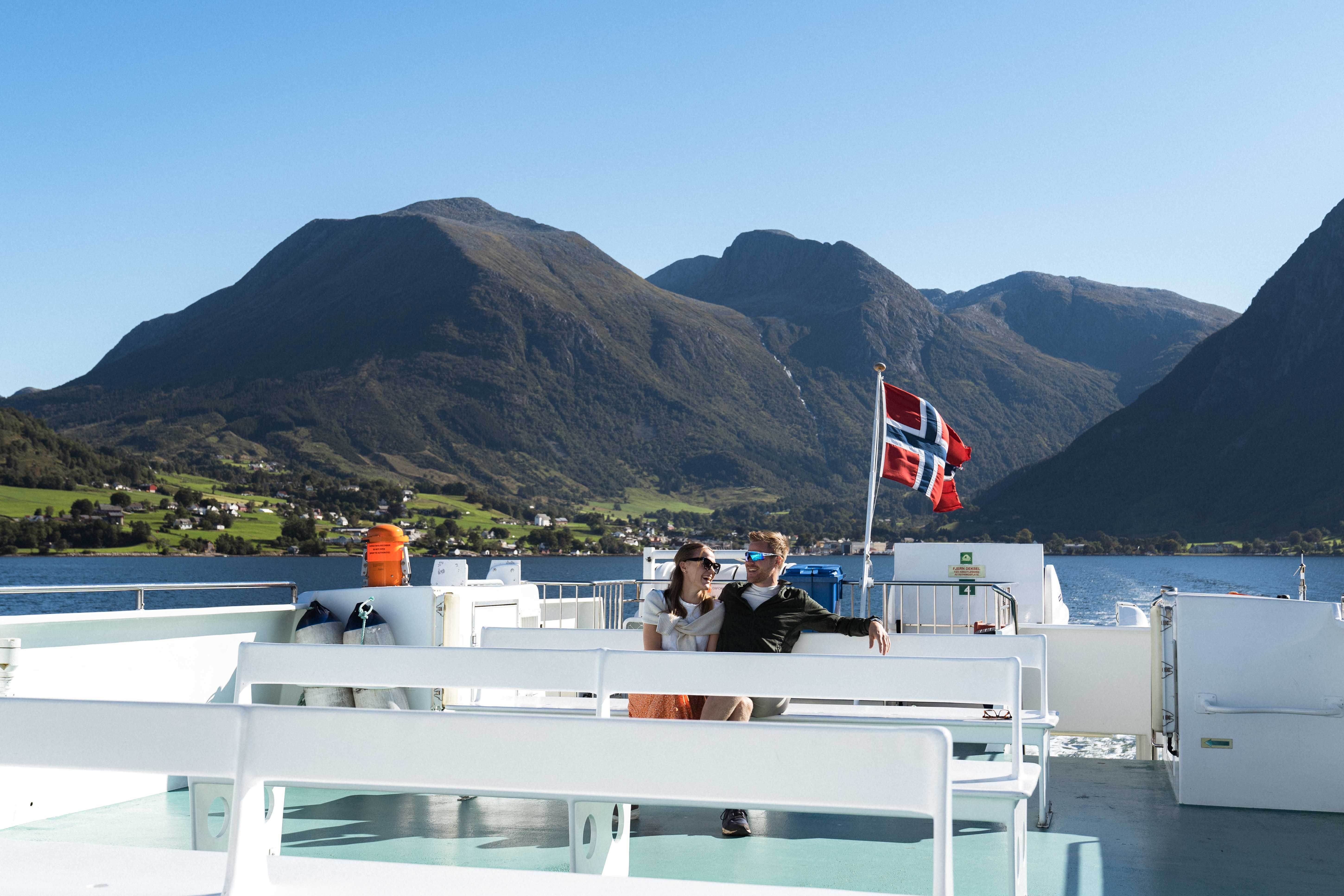 A couple sitting on deck enjoying the beautiful view of the Hardangerfjord and Norwegian nature.