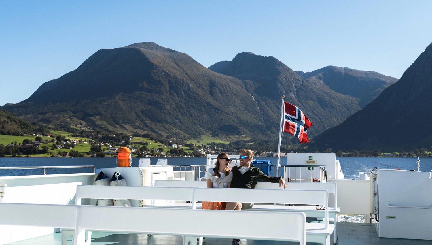 A couple sitting on deck enjoying the beautiful view of the Hardangerfjord and Norwegian nature.