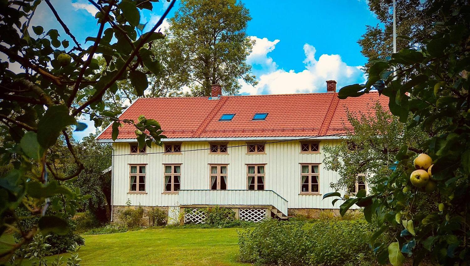 Langt hvitt hus med mange vinduer og mursteintak