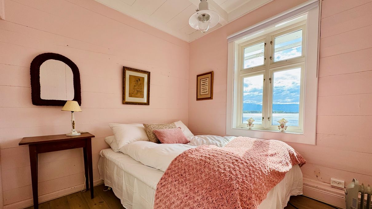 The Pink Room at Kramsjø Guesthouse, featuring soft pastel tones and a view towards the fjord.