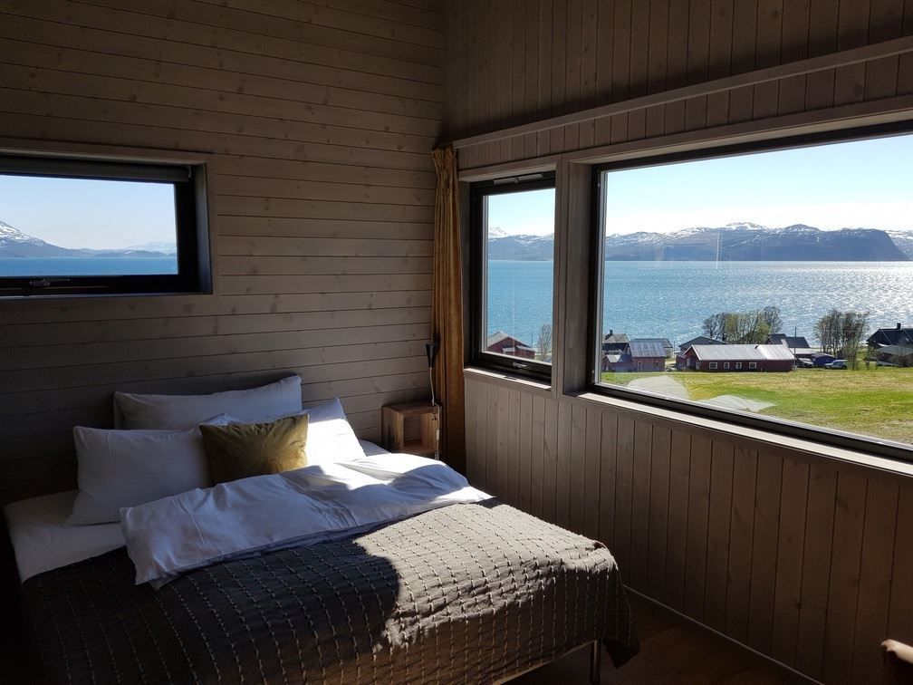 Bedroom with a view of a lake and mountains through large windows