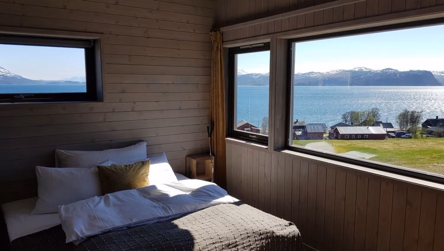 Bedroom with a view of a lake and mountains through large windows