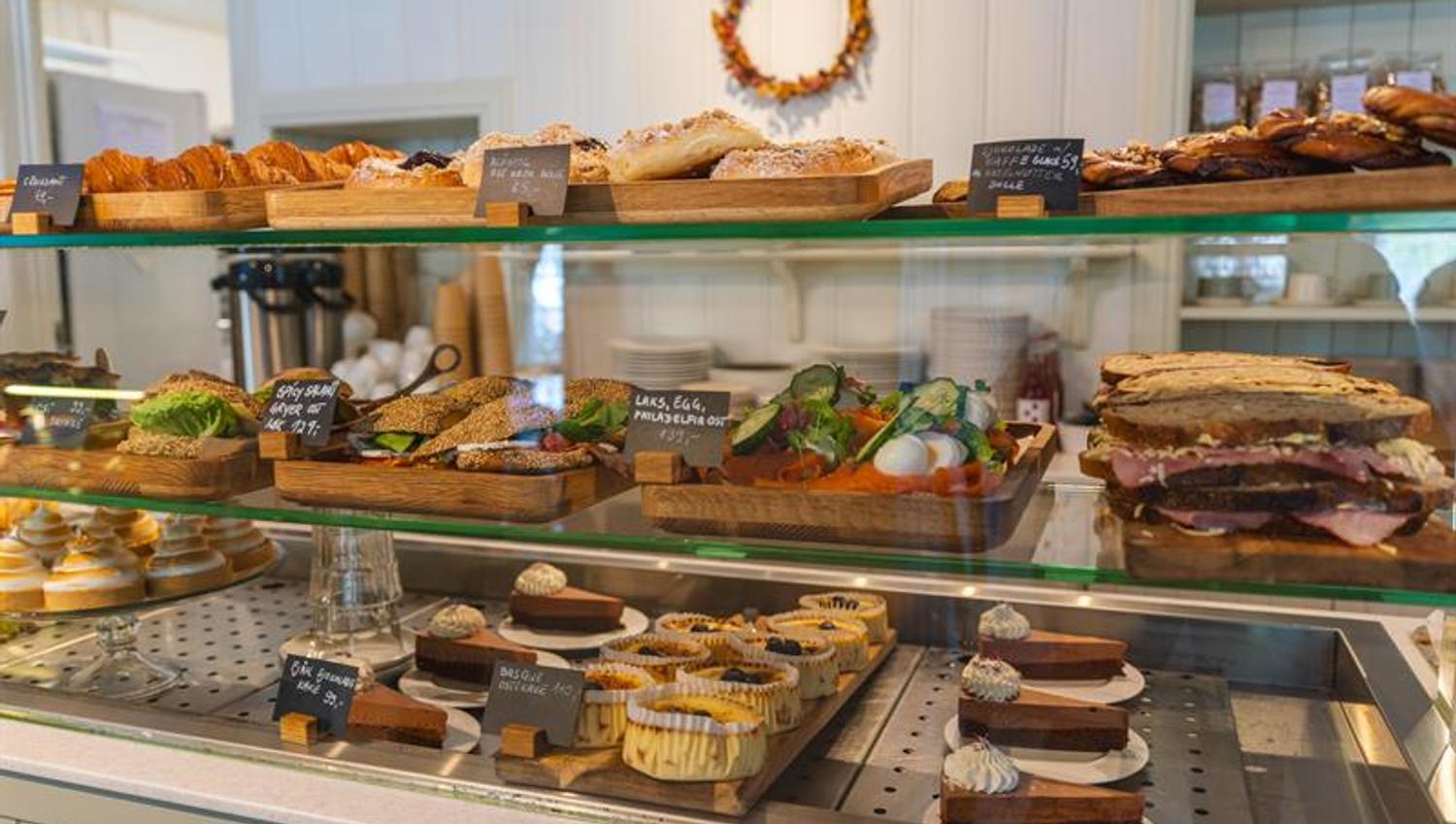 A display counter filled with sandwiches, cakes, and a variety of baked goods.