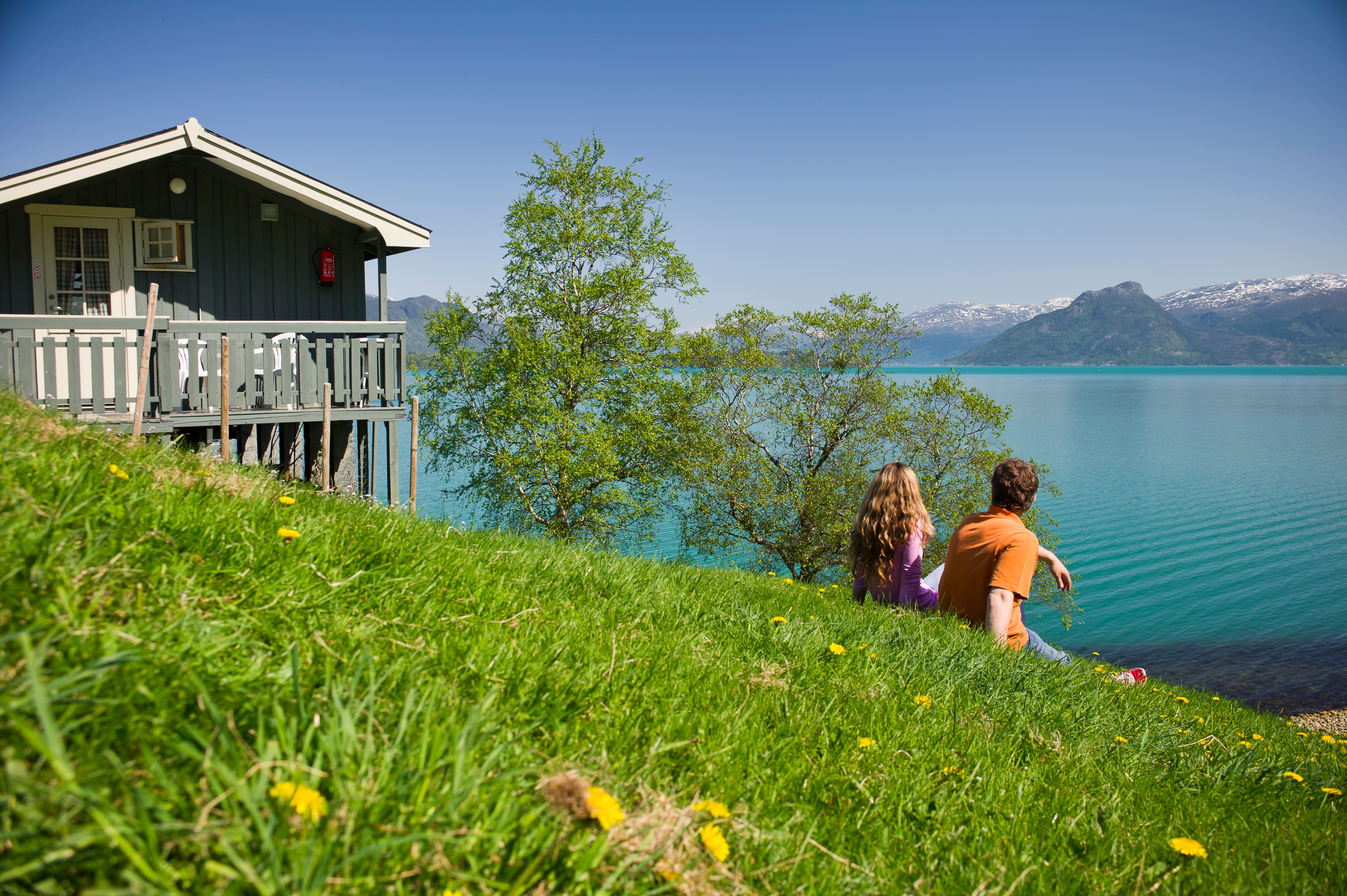 Couple enjoying the view from Oddland Camping overlooking the fjord and snow-capped mountains.