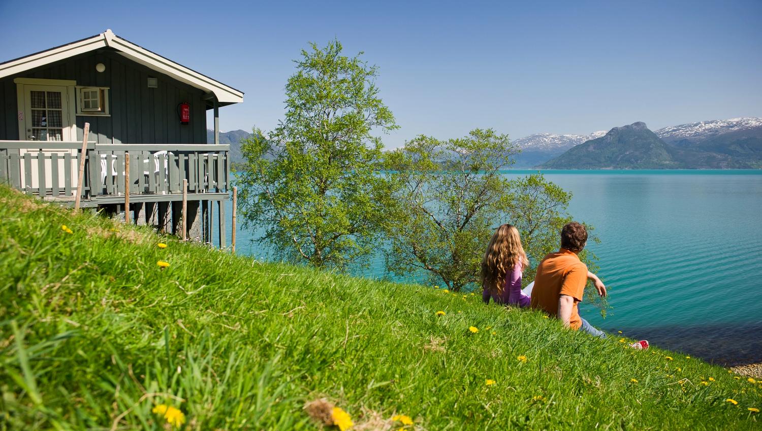 Couple enjoying the view from Oddland Camping overlooking the fjord and snow-capped mountains.