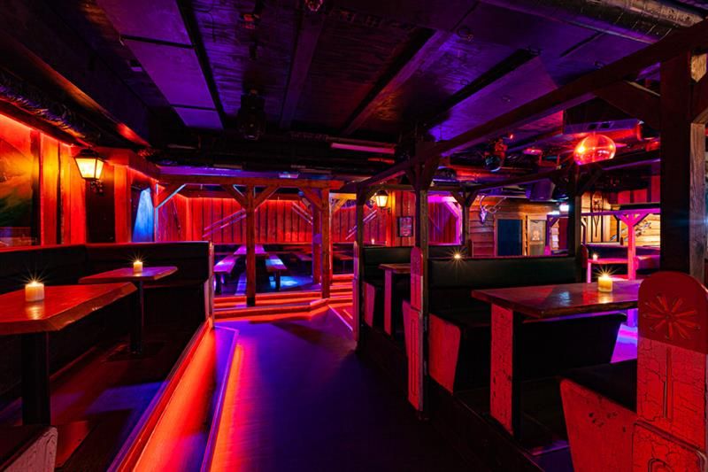 Bar interior with seating booths surrounded by neon lights