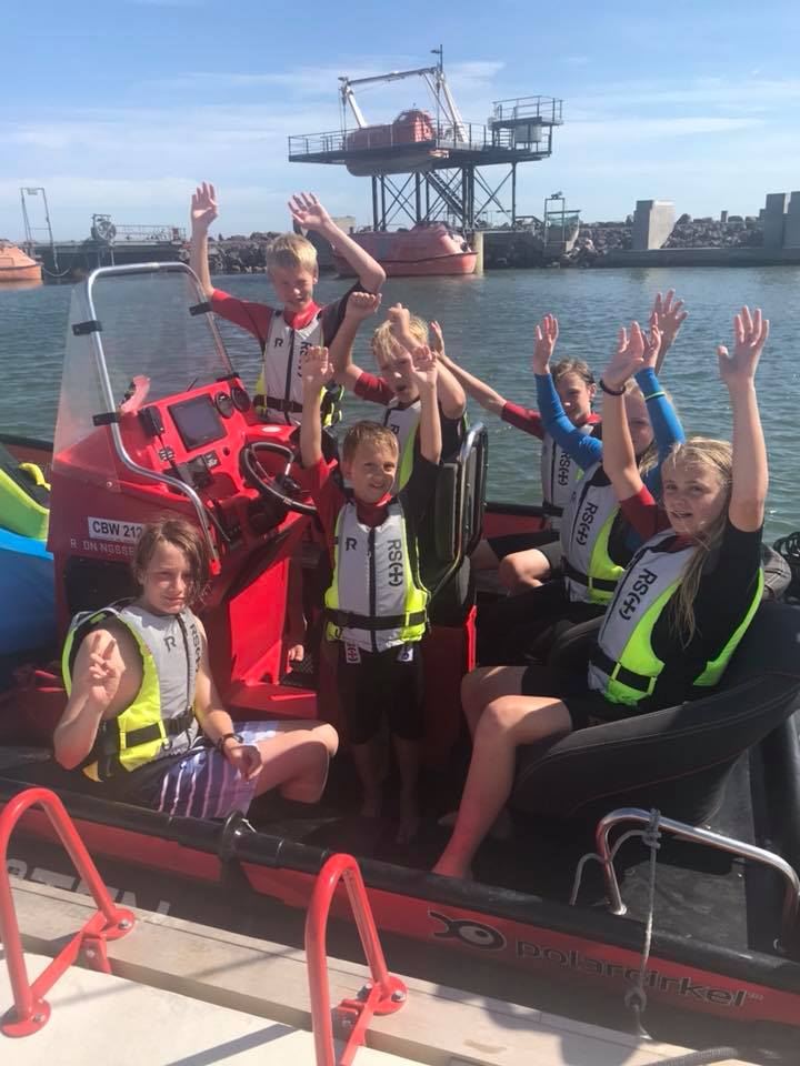 Children with life jackets in a boat at the wharf