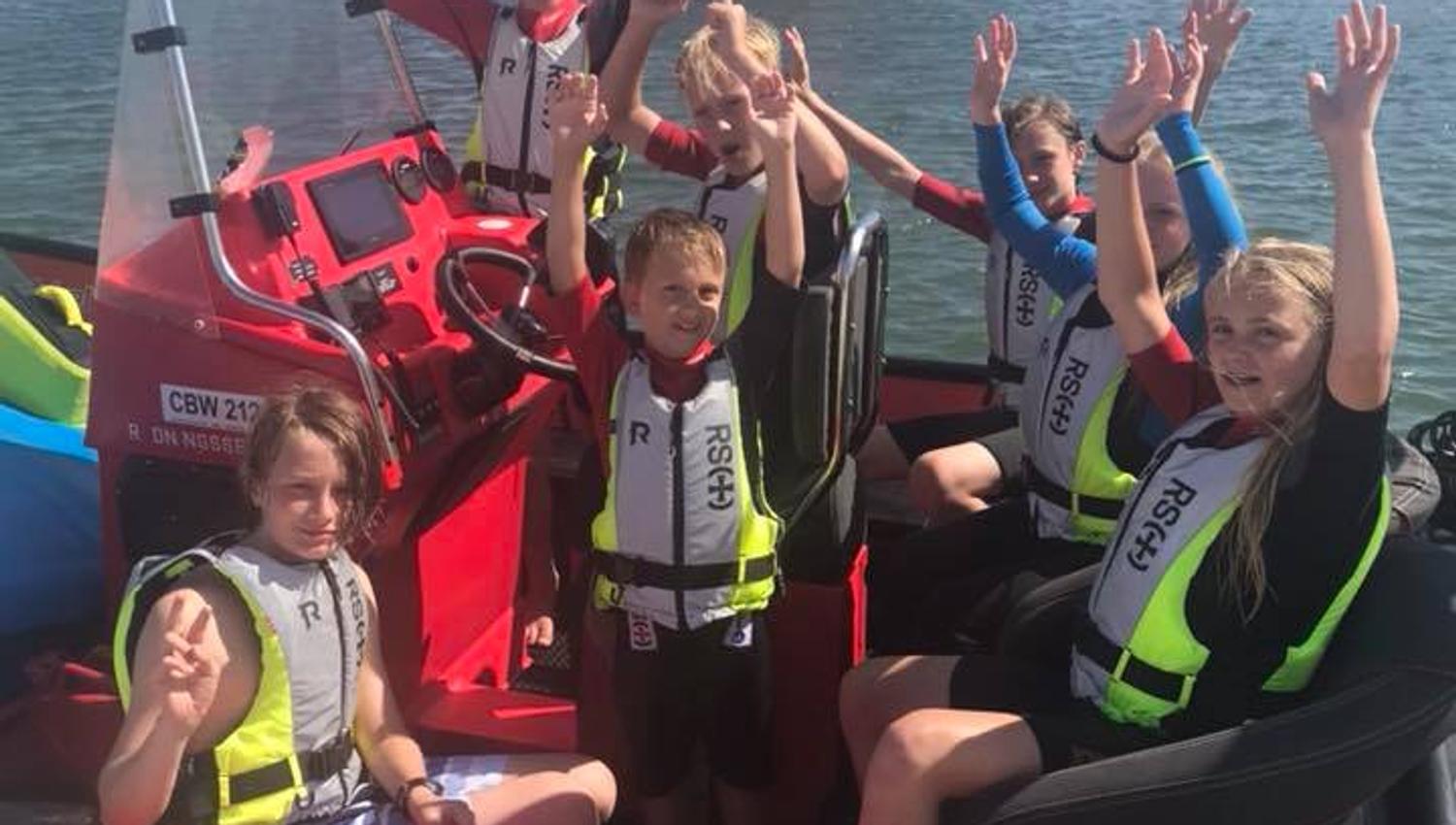 Children with life jackets in a boat at the wharf