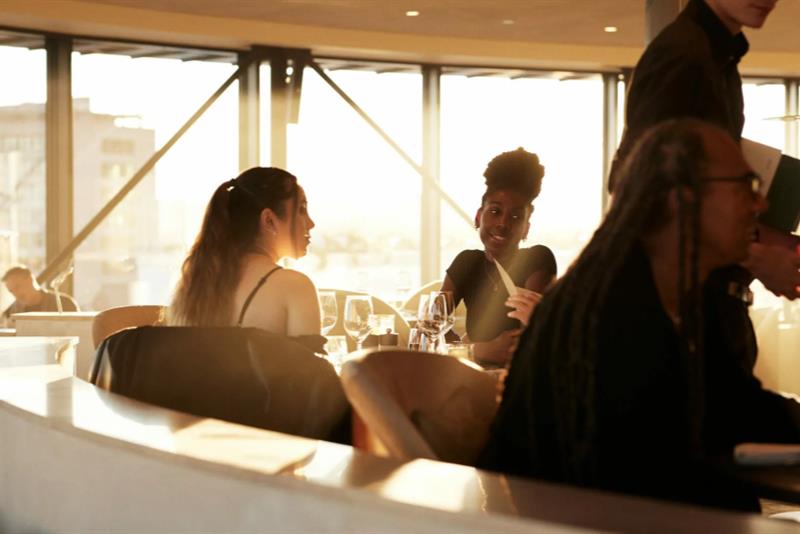 People eating while the sun shines through the window.