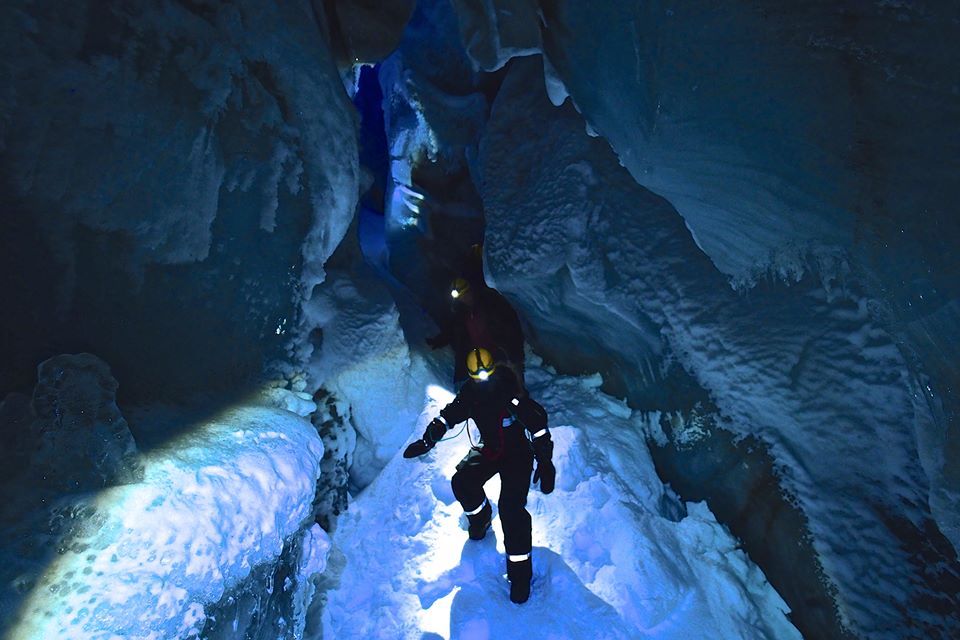 Persons inside the ice cave with headlamps on