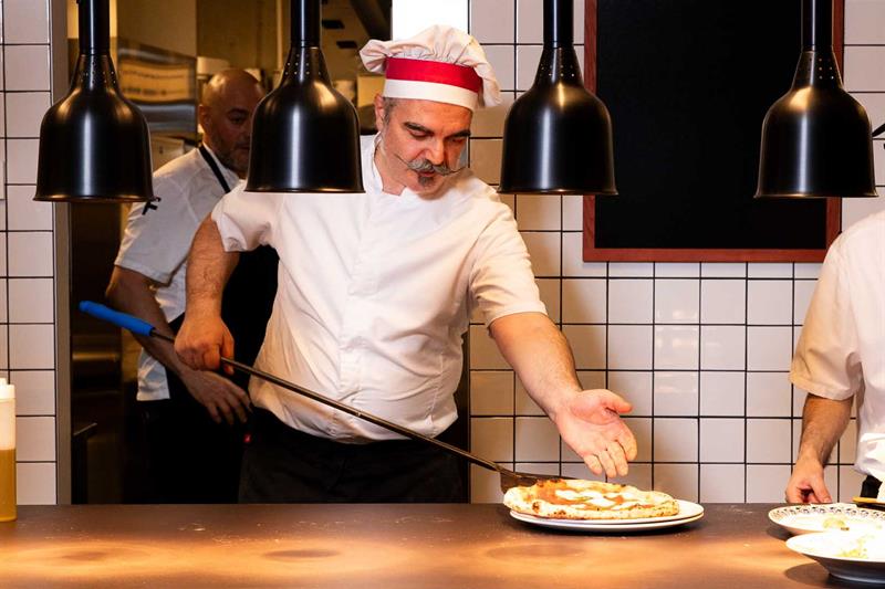 Chef Francesco De Palma taking a pizza out of the oven