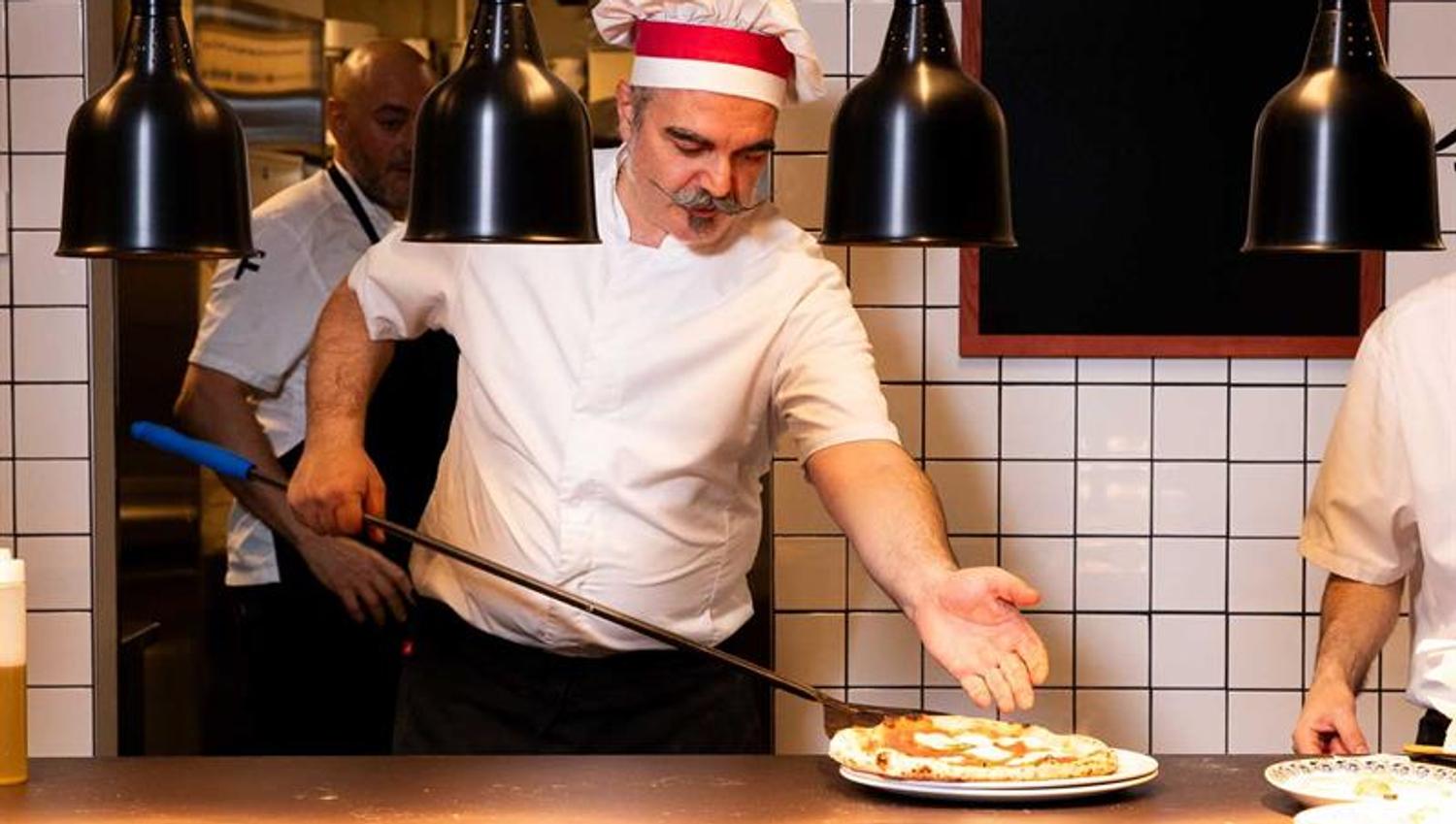 Chef Francesco De Palma taking a pizza out of the oven