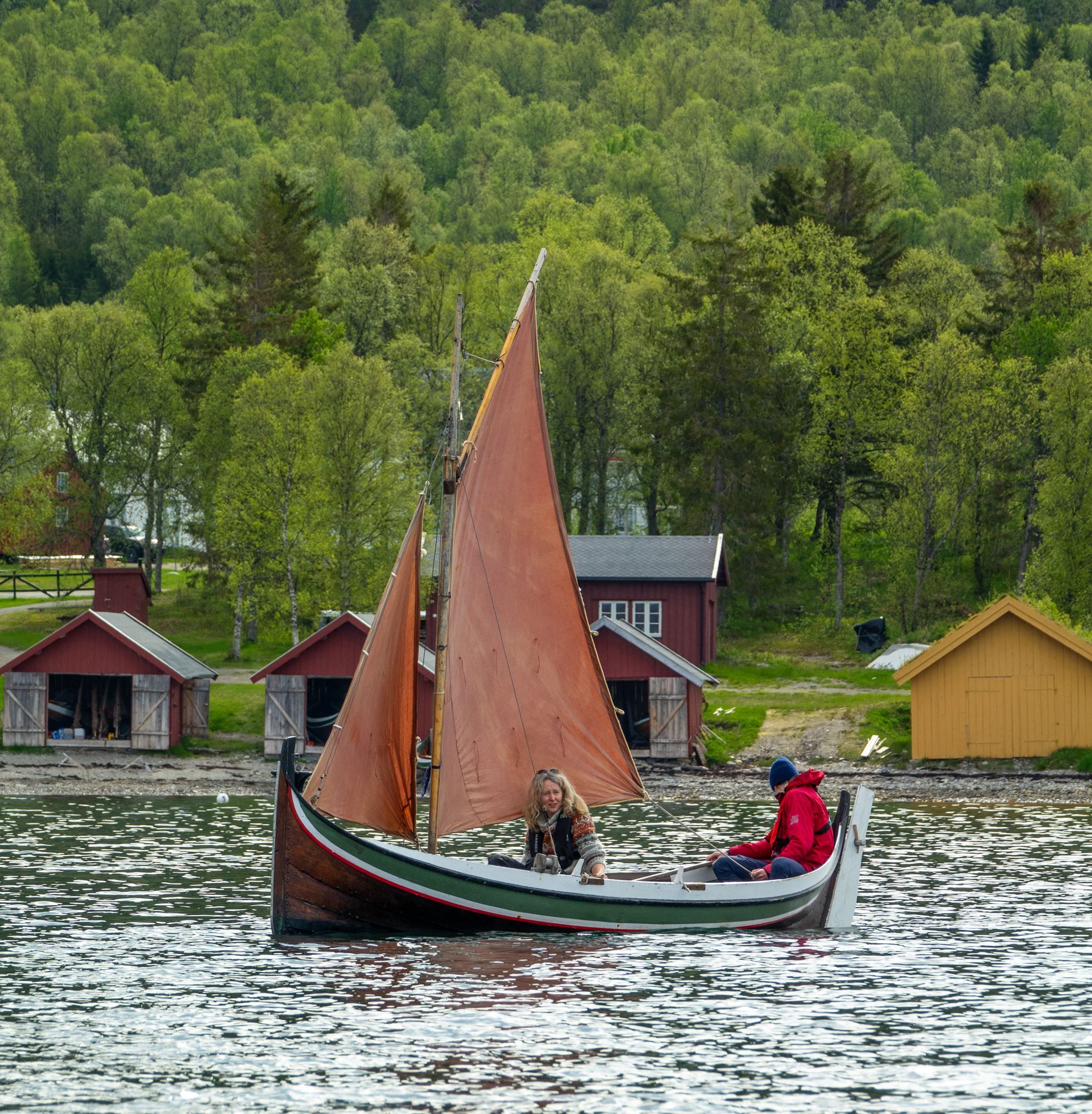 Two people sailing a traditional small boat.