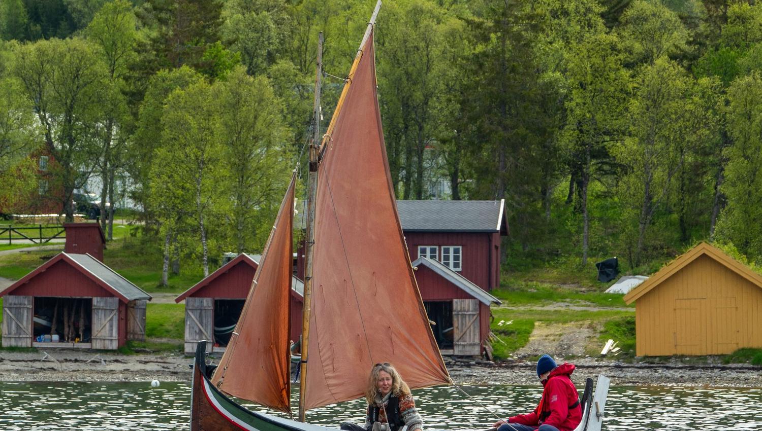 Two people sailing a traditional small boat.