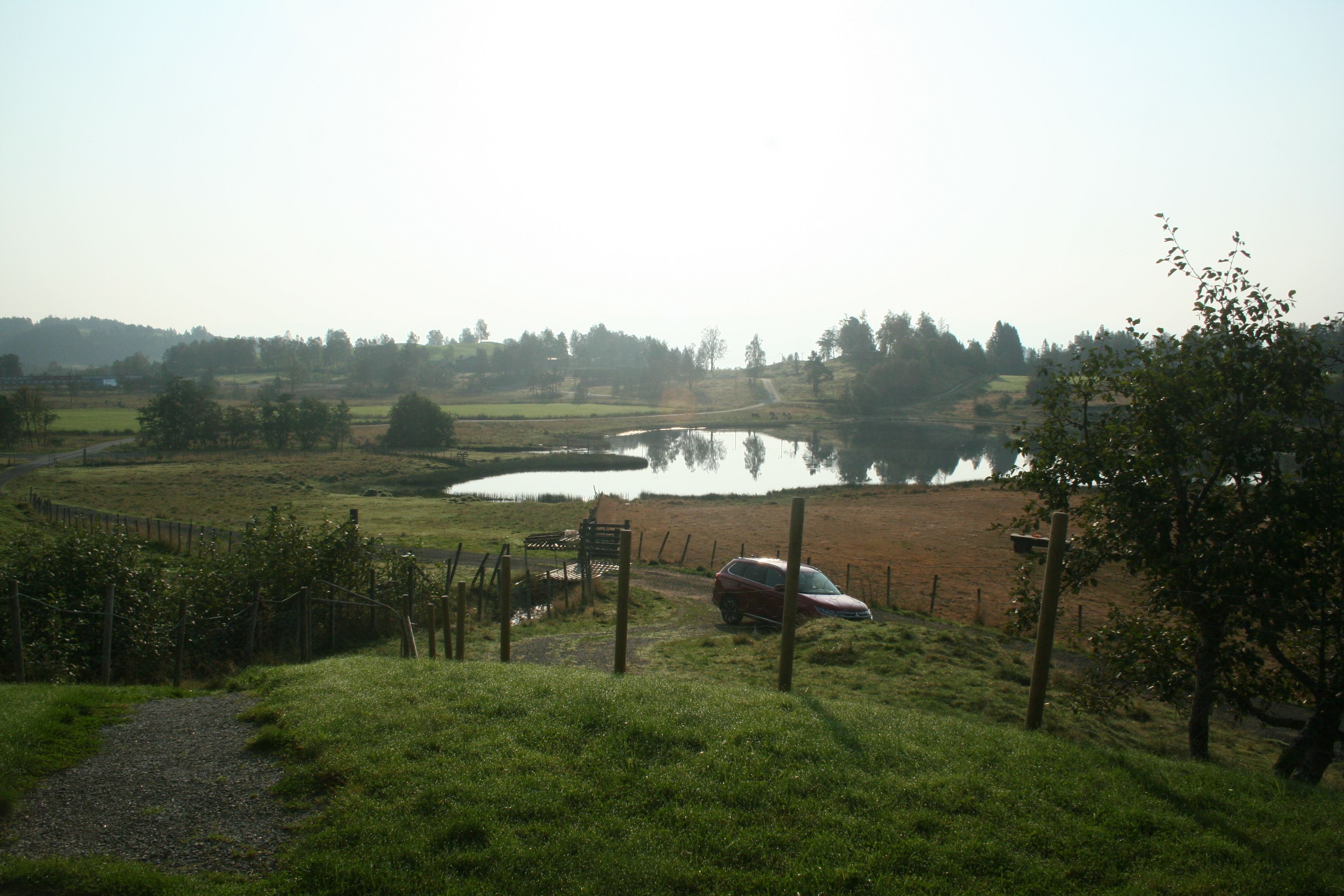 View from Sjusete Cabins over a picturesque lake with rolling hills and forest in the distance.