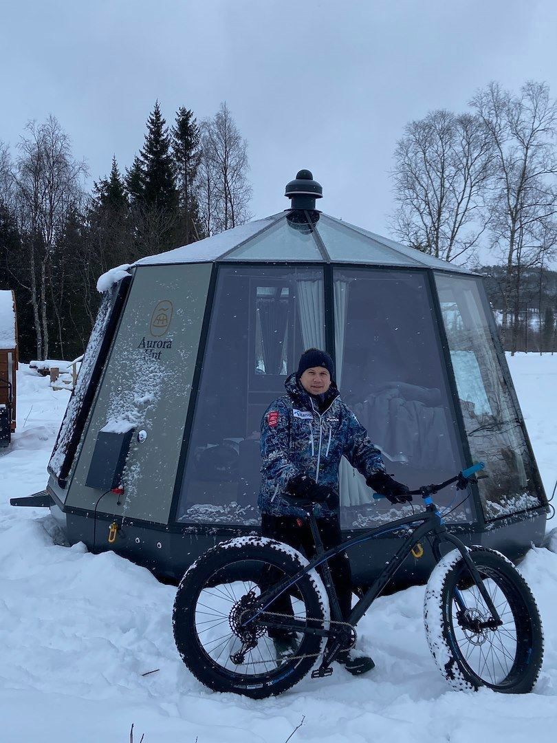 A man with a fatbike outside one of the glass iglos at North Experience