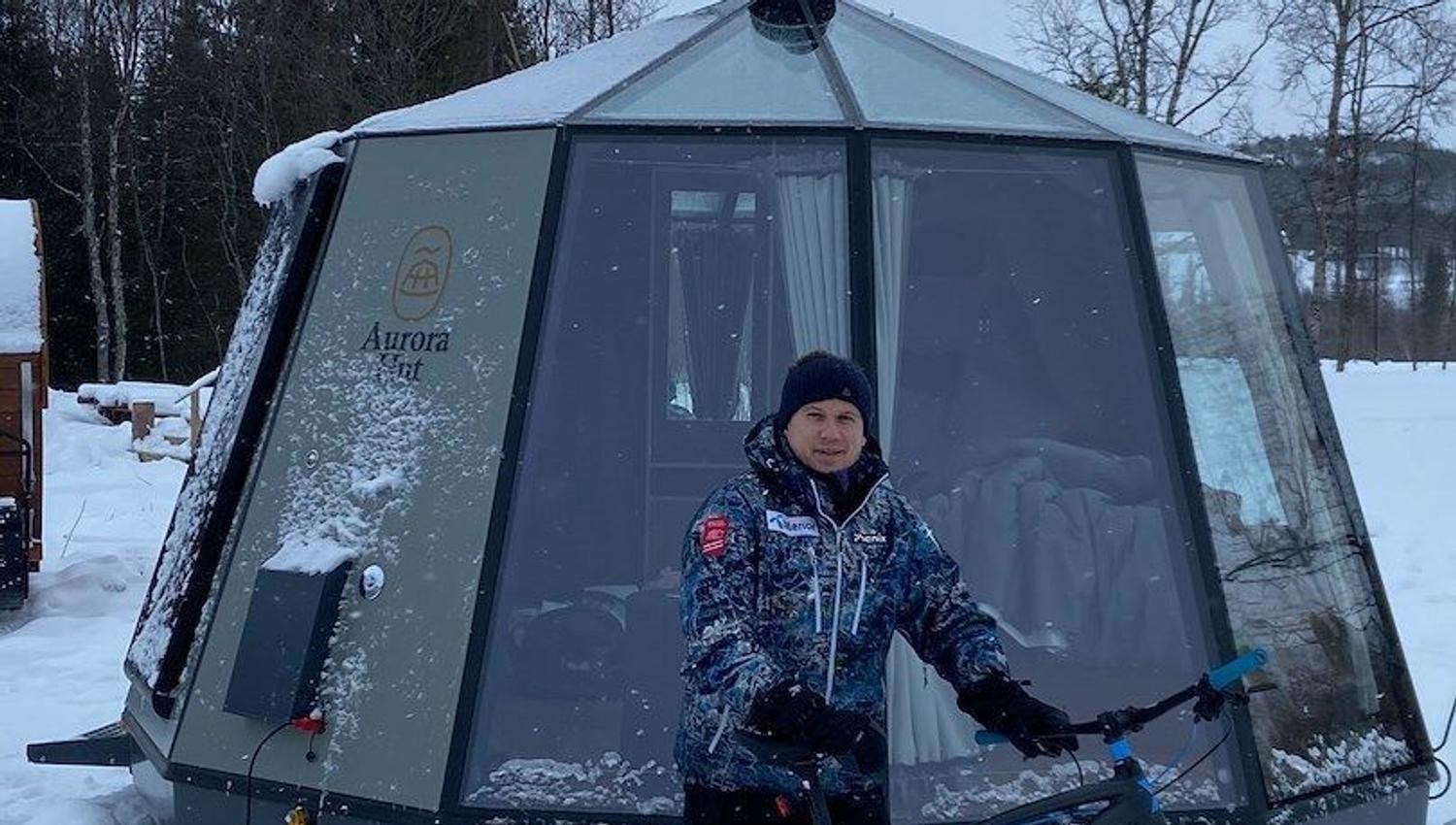 A man with a fatbike outside one of the glass iglos at North Experience