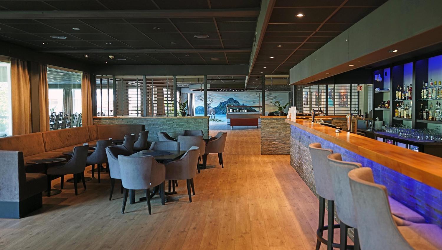 Moderne restaurantlounge på Bremanger Fjordhotell i Svelgen med bar til høgre, bord og stolar til venstre, tregolv og dempa belysning..