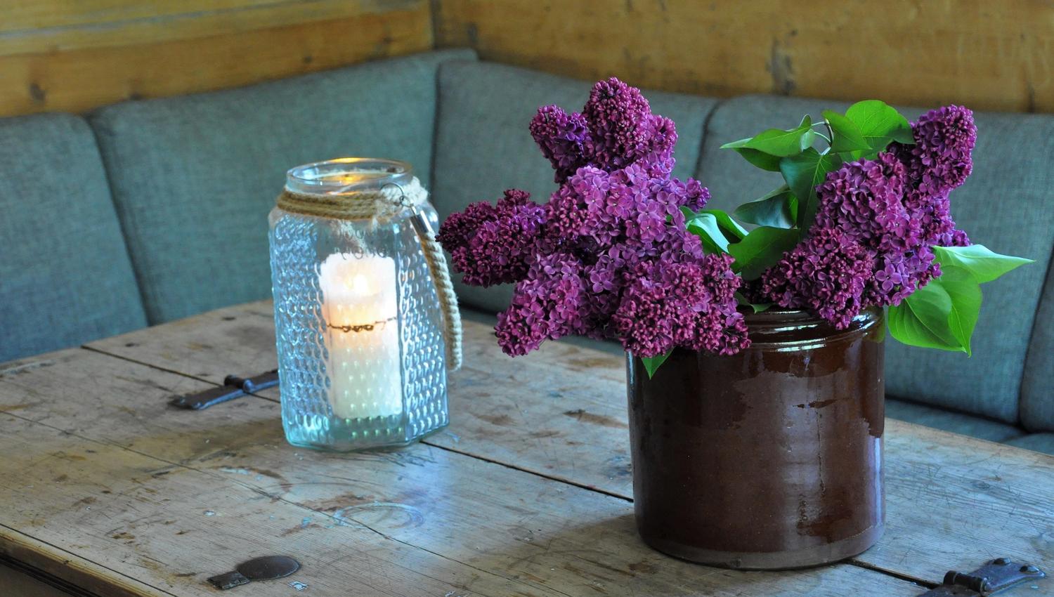 A sofa by a table with flowers and a candle