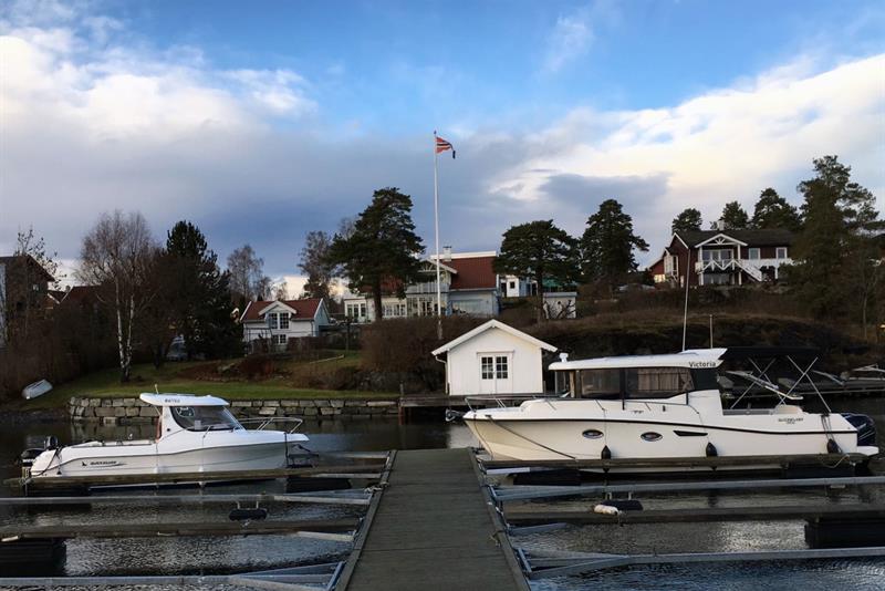 jetty with boats moored in port and houses in the background