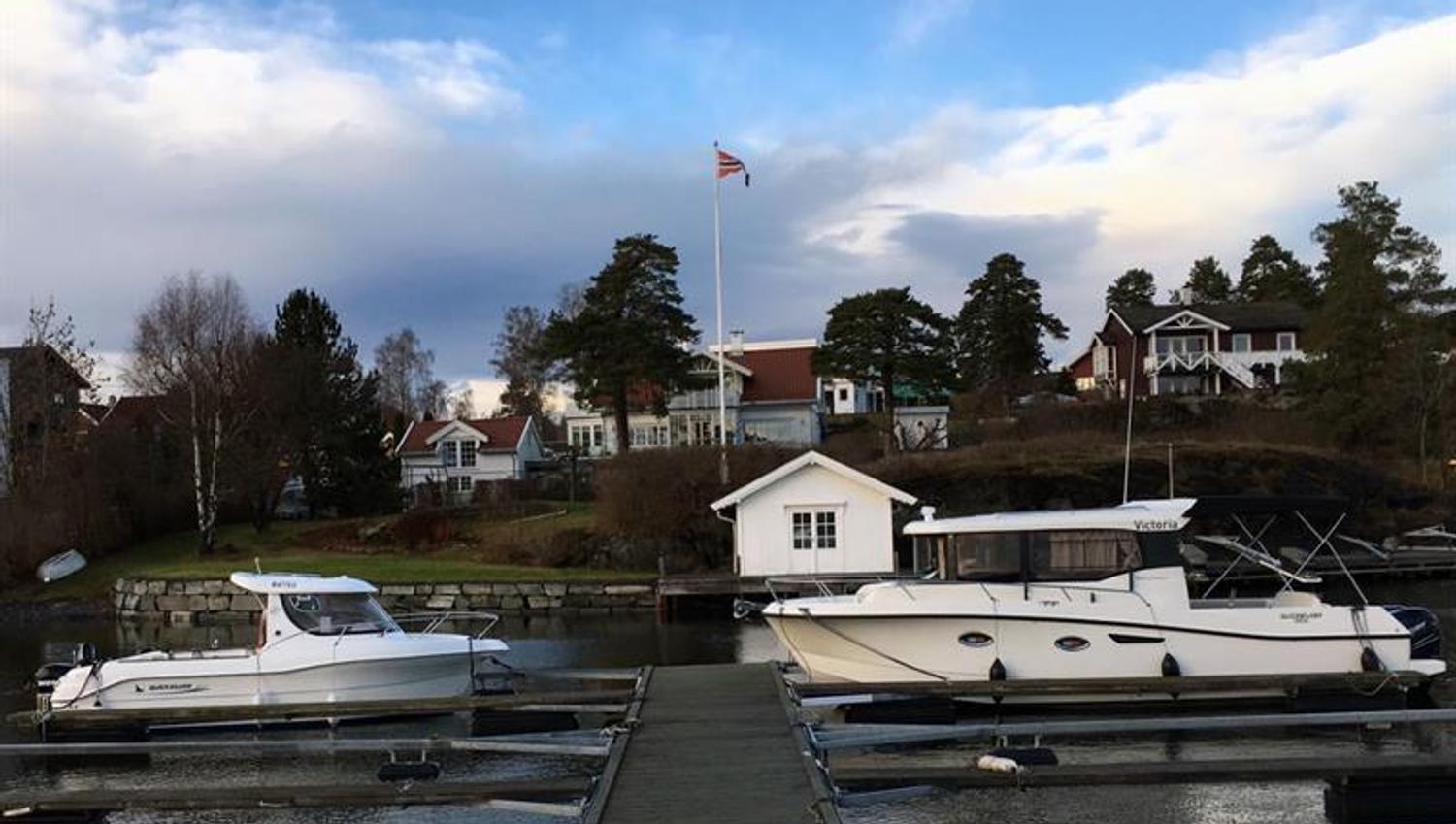jetty with boats moored in port and houses in the background