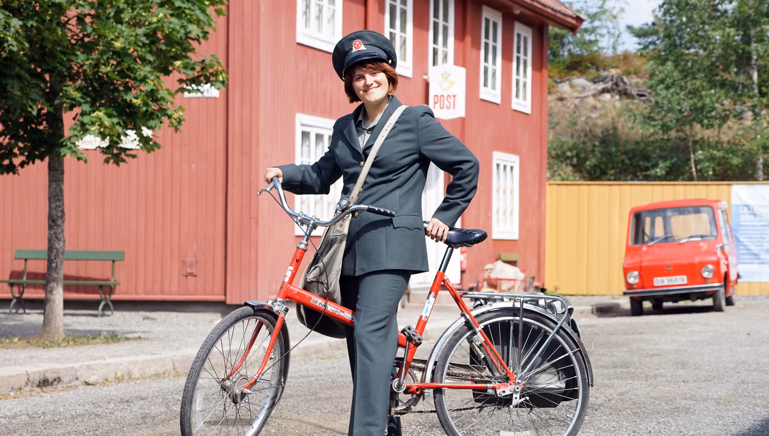 Post woman in historical uniform in front of the Postal Museum at Maihaugen.