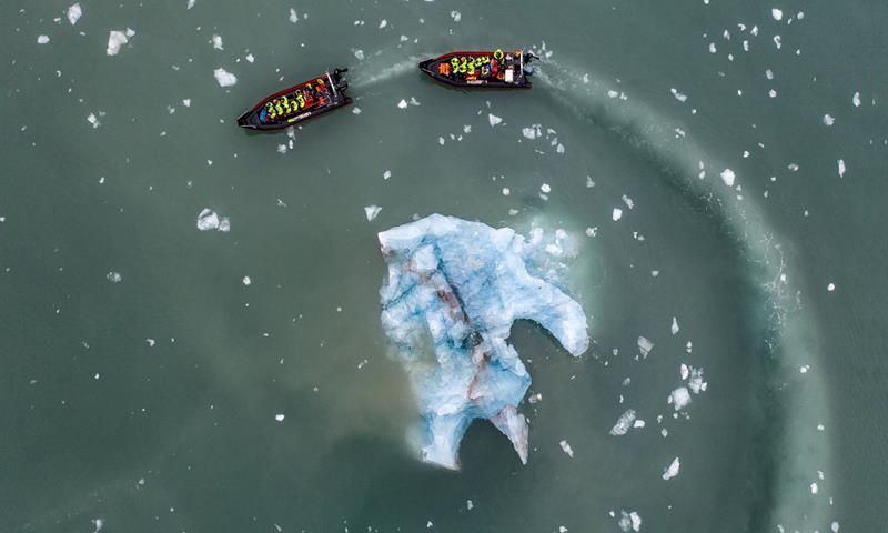 To RIB båter seiler rundt en stor isklump