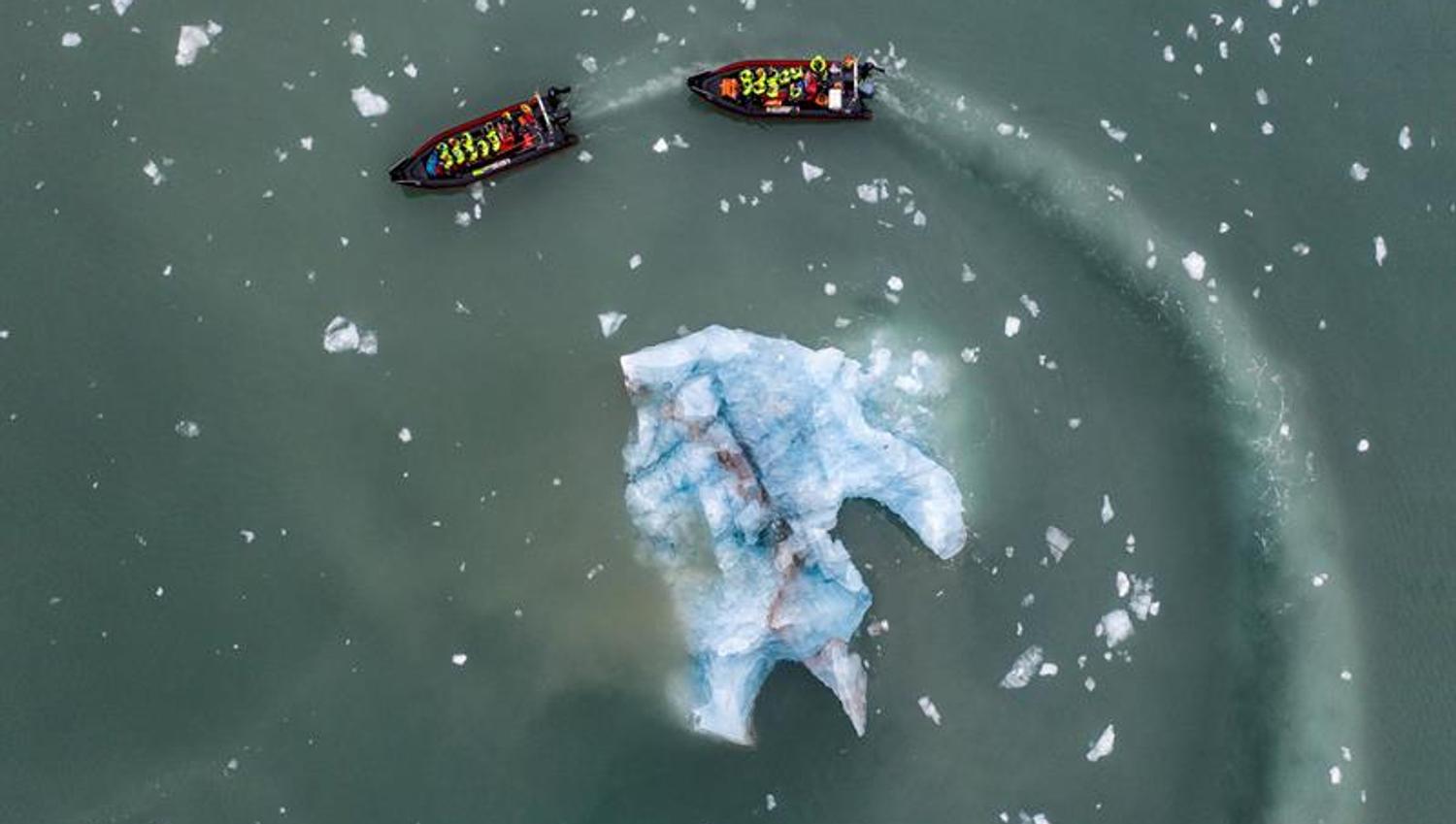 To RIB båter seiler rundt en stor isklump