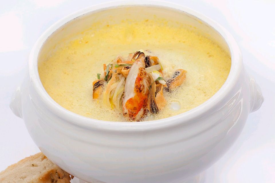 Detail photo of a bowl filled with soup, with two pieces of bread next to it.