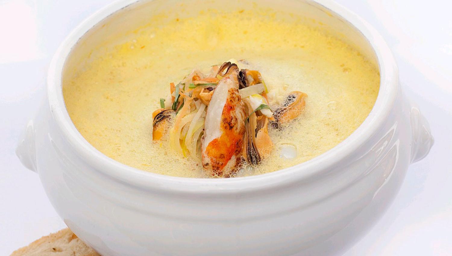 Detail photo of a bowl filled with soup, with two pieces of bread next to it.