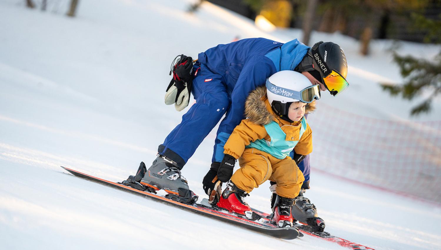 father teaches children to ski