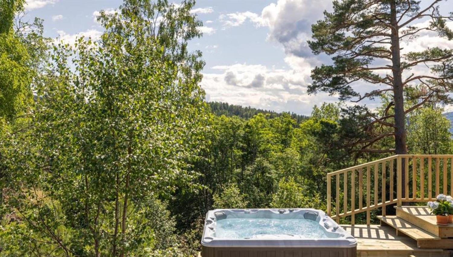 A hot tub on a terrace surrounded by trees with a view of the landscape.
