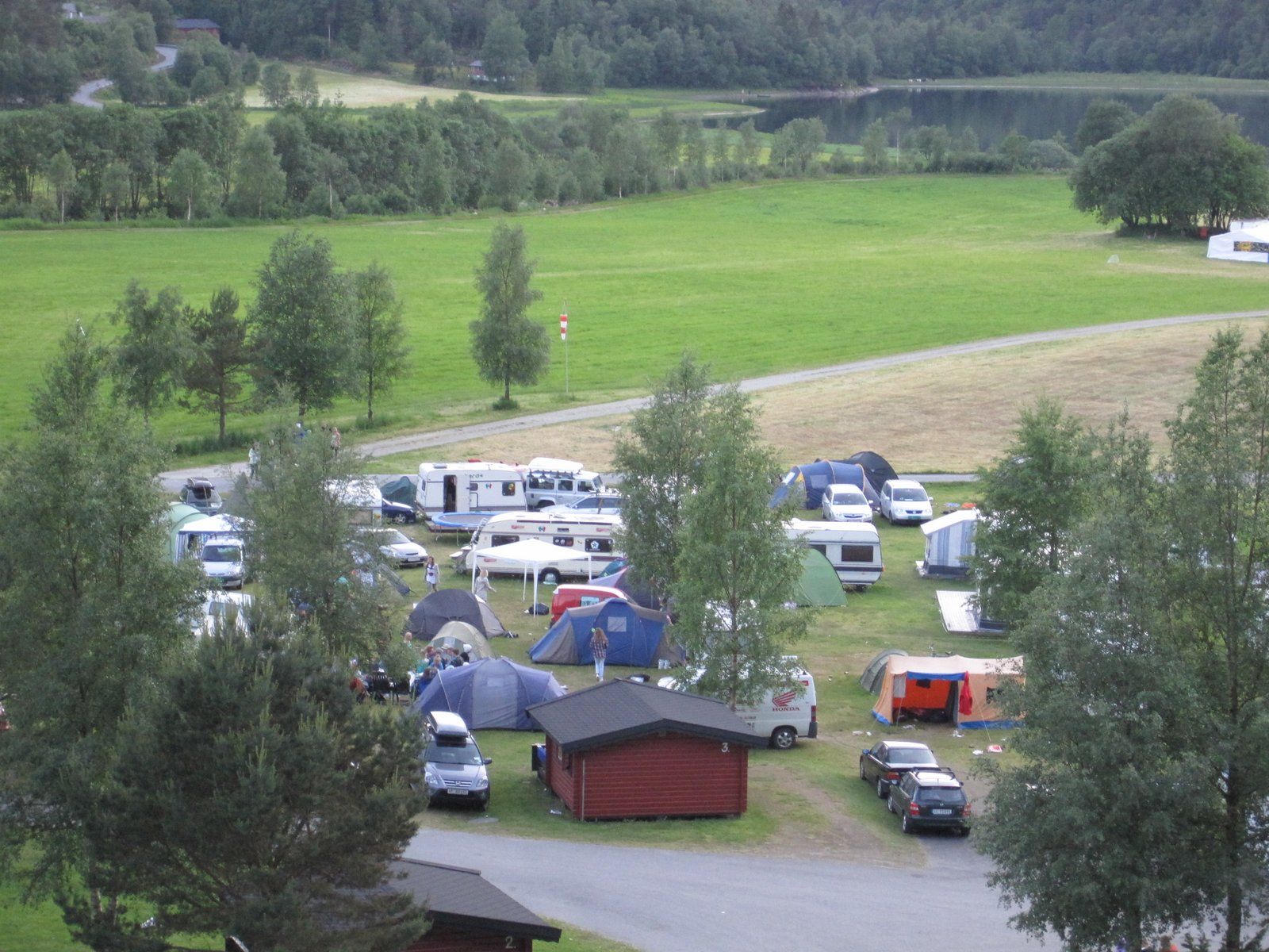 Overview of the campsite with tents, campervans, and cabins at Folgefonn Cabins and Farm Camping in Hardanger.
