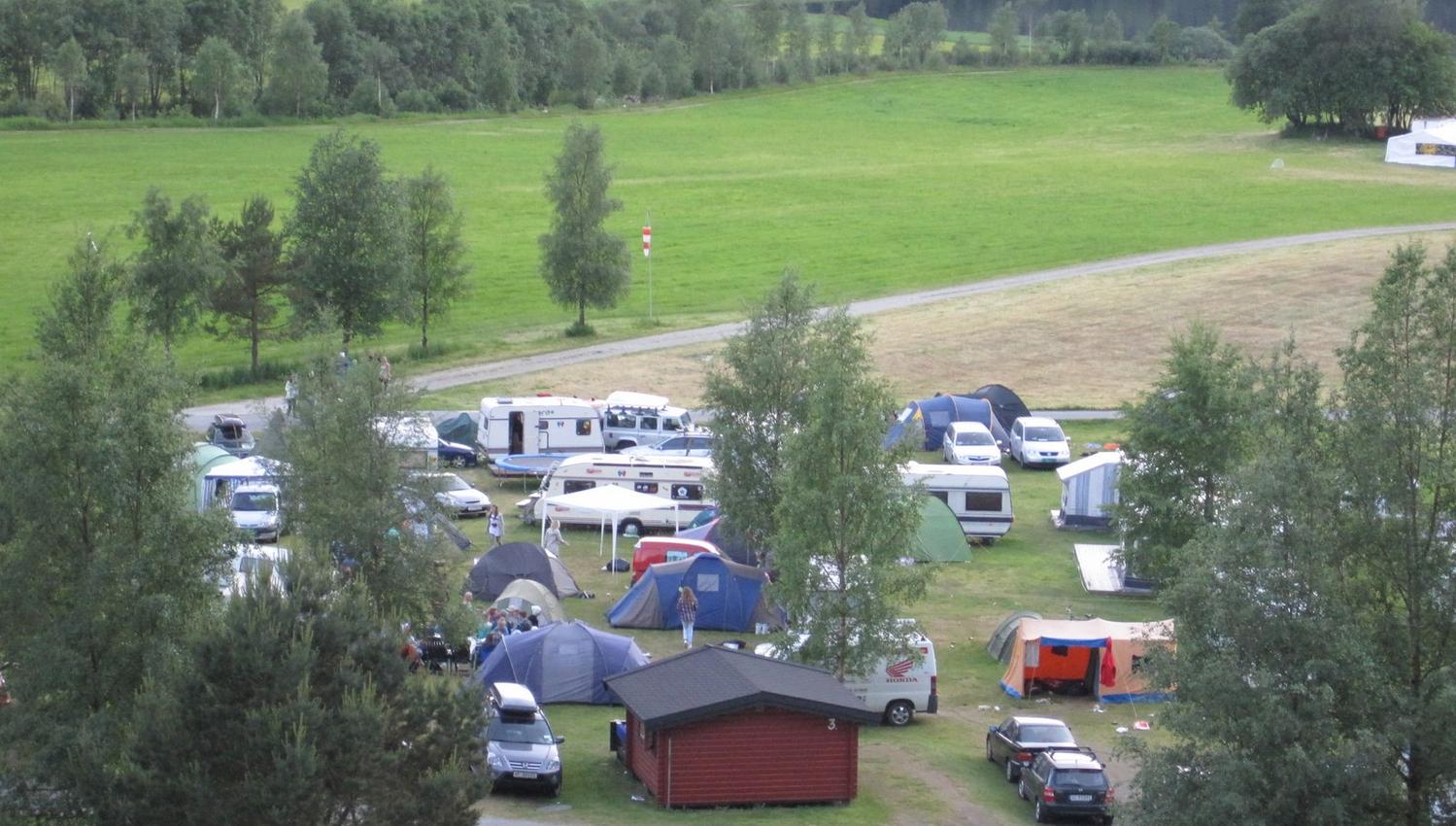 Overview of the campsite with tents, campervans, and cabins at Folgefonn Cabins and Farm Camping in Hardanger.