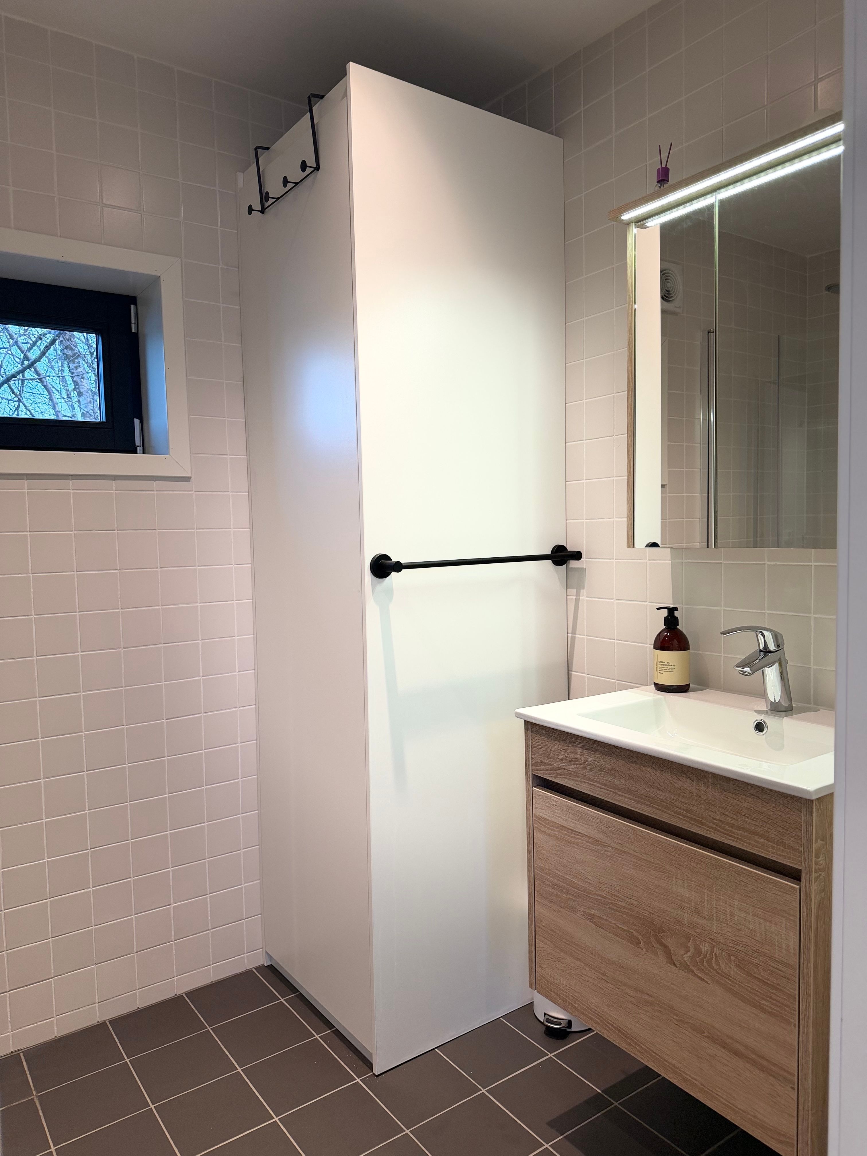 Moderne badkamer met een witte kast, spiegel en houten wastafel.