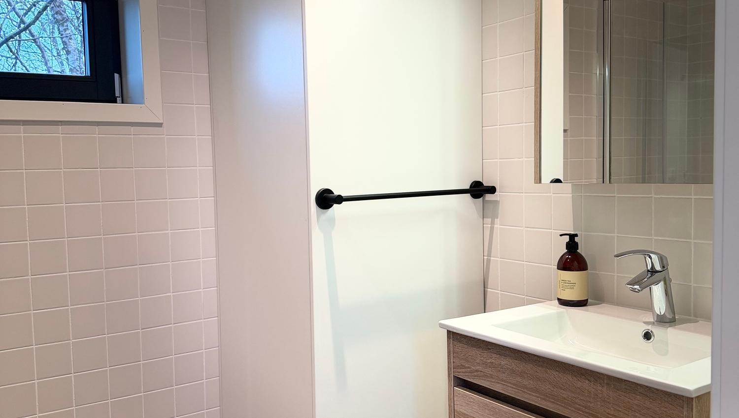 Moderne badkamer met een witte kast, spiegel en houten wastafel.